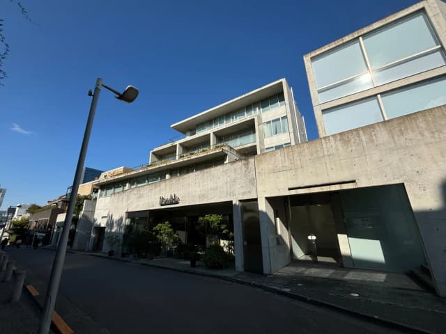 現代的な外観のオフィスビル、コンクリートのファサードに大きな窓、青空の下での都市風景
