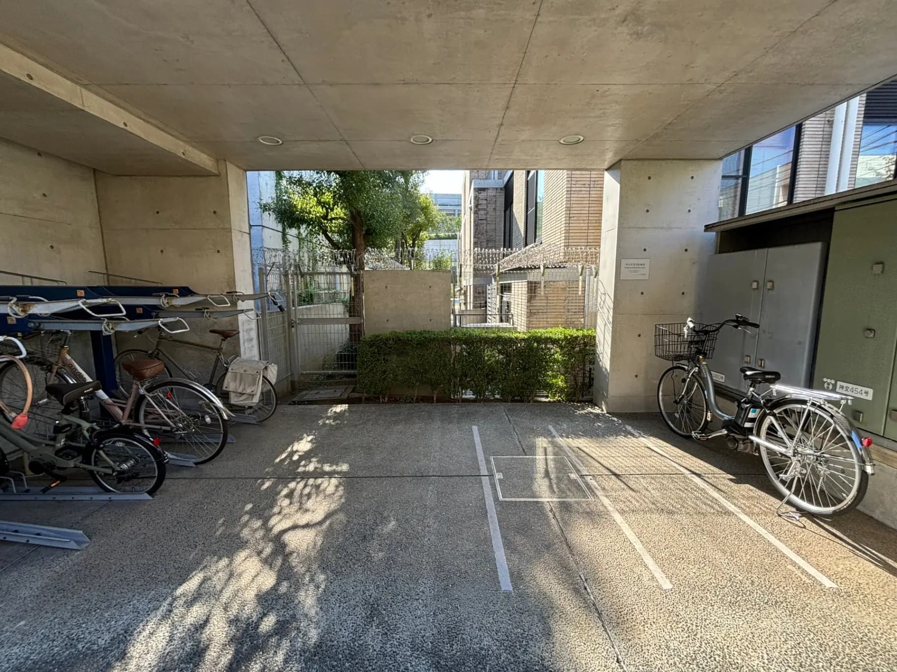 コンクリート構造の自転車駐輪場、日陰と日差しのコントラスト、都市型アパートメントの一部