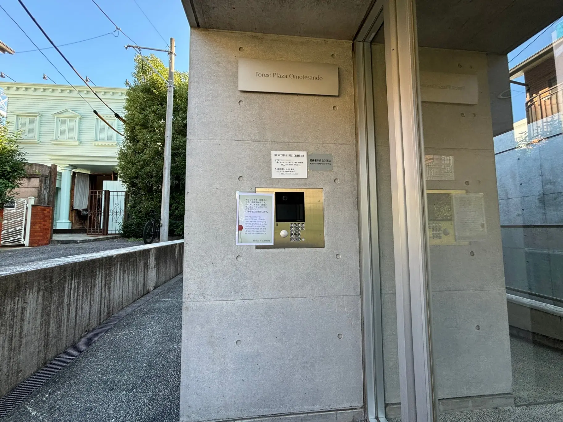 建物の入り口とインターホン、横には説明看板がある都市のアパートメント