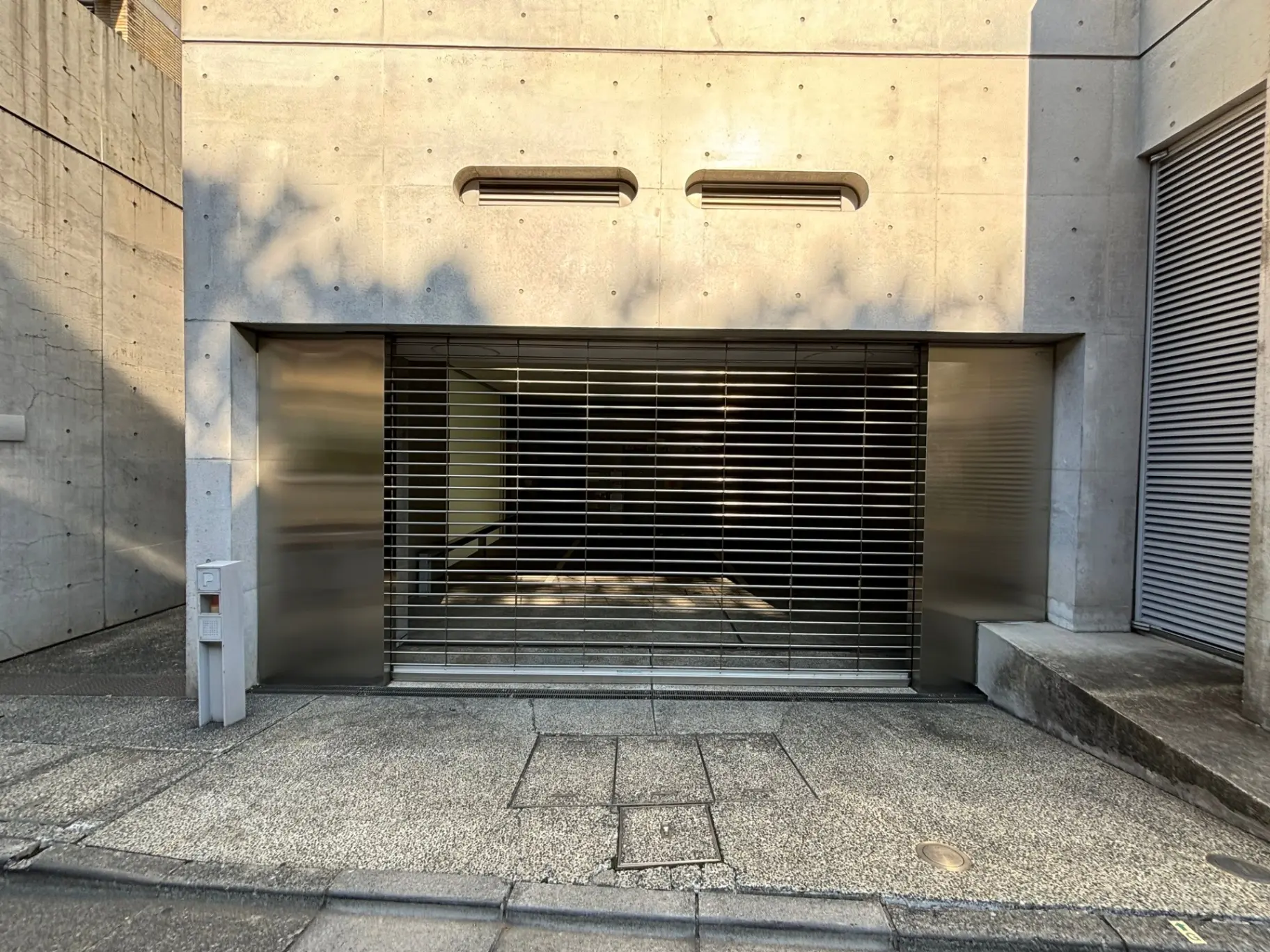 現代的な建築スタイルのビルのエントランス、シャッターとクリアなガラスが特徴的なファサード