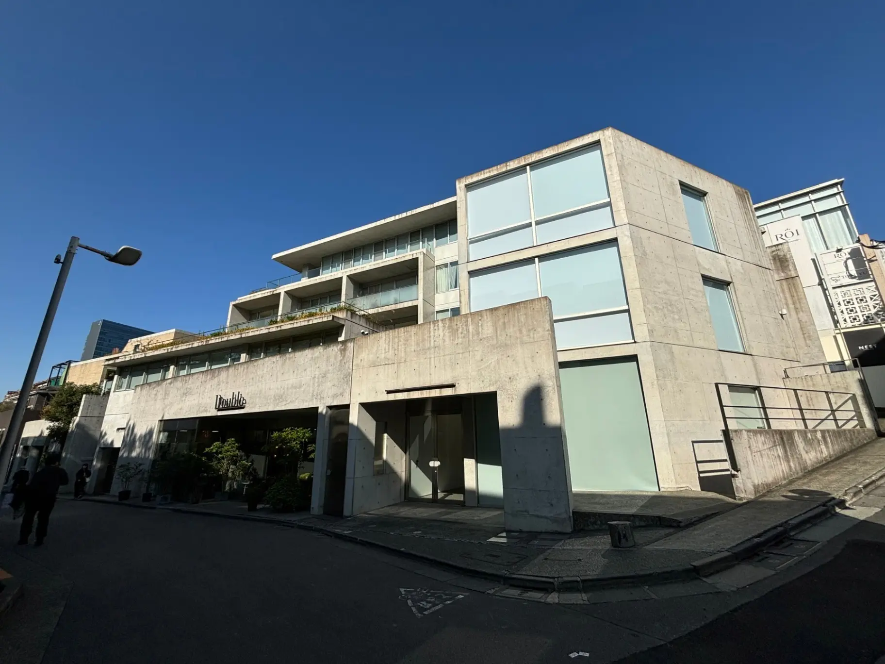 コンクリート打ち放しのモダンな建物外観、ガラス窓、晴れた空と都市の住宅街