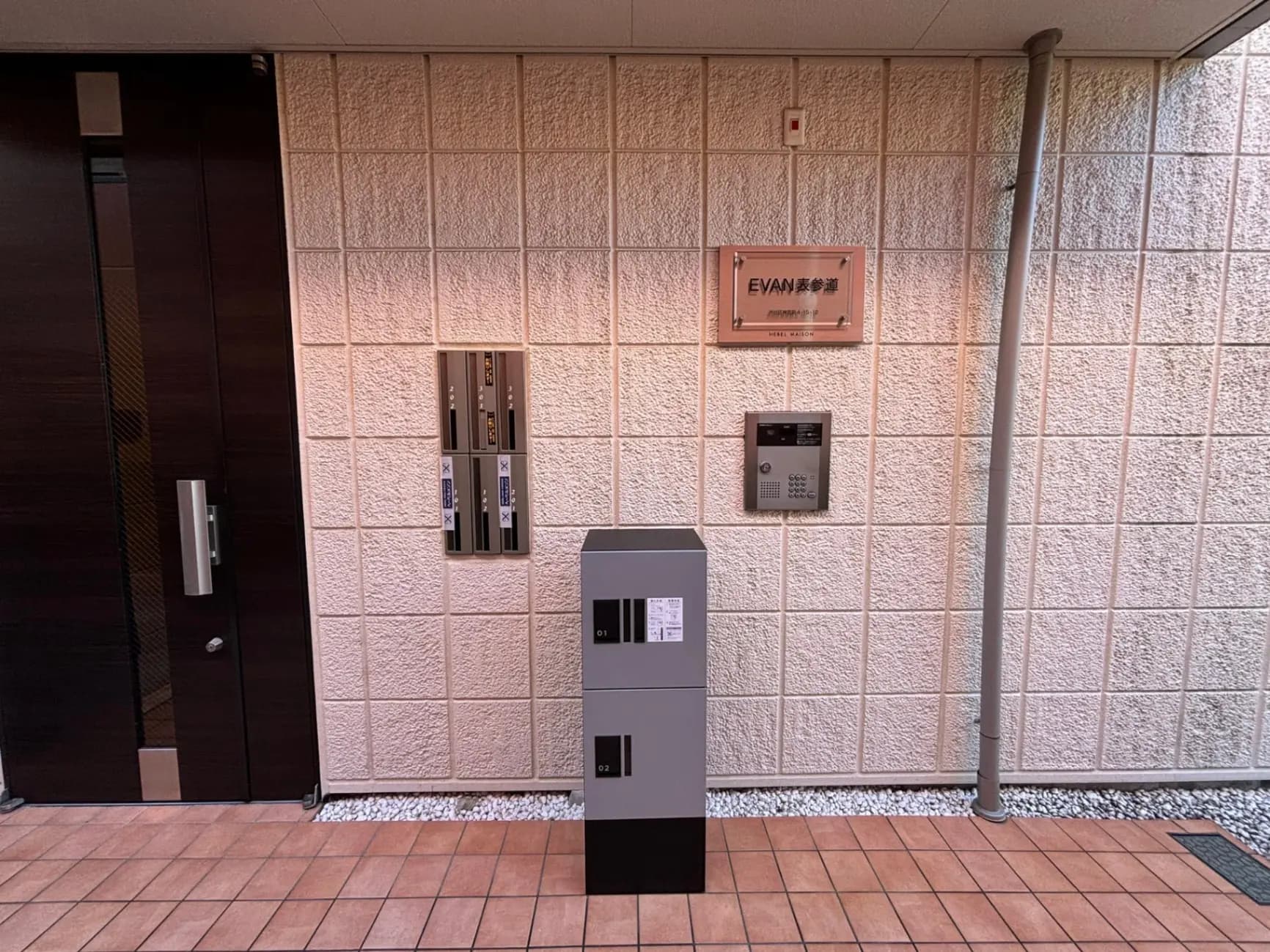マンションのエントランスにあるインターホンと宅配ボックス、モダンなデザインの建物外観