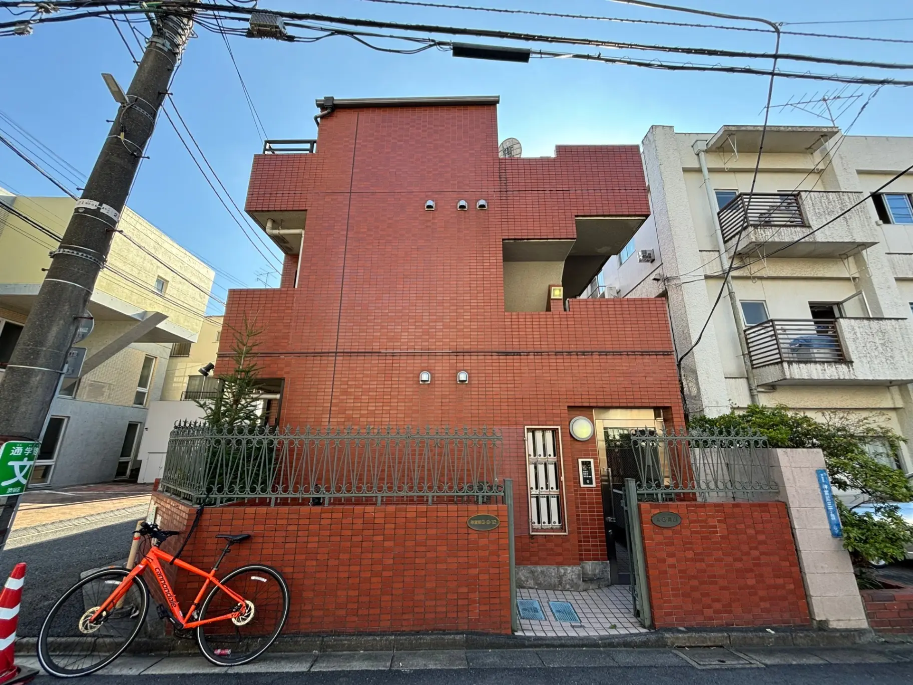 都市のレンガ造りのアパートビル、オレンジ色の自転車がフェンスに寄りかかっている外観