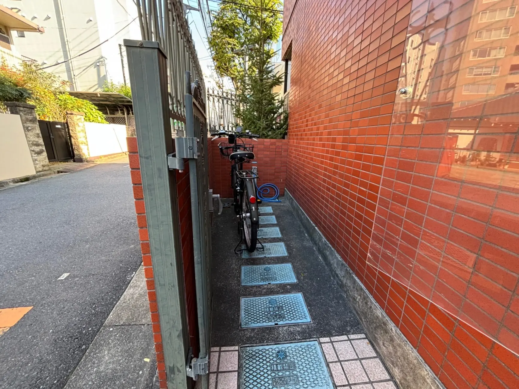 都市の狭い路地と赤いタイル壁、駐輪された自転車が見える風景