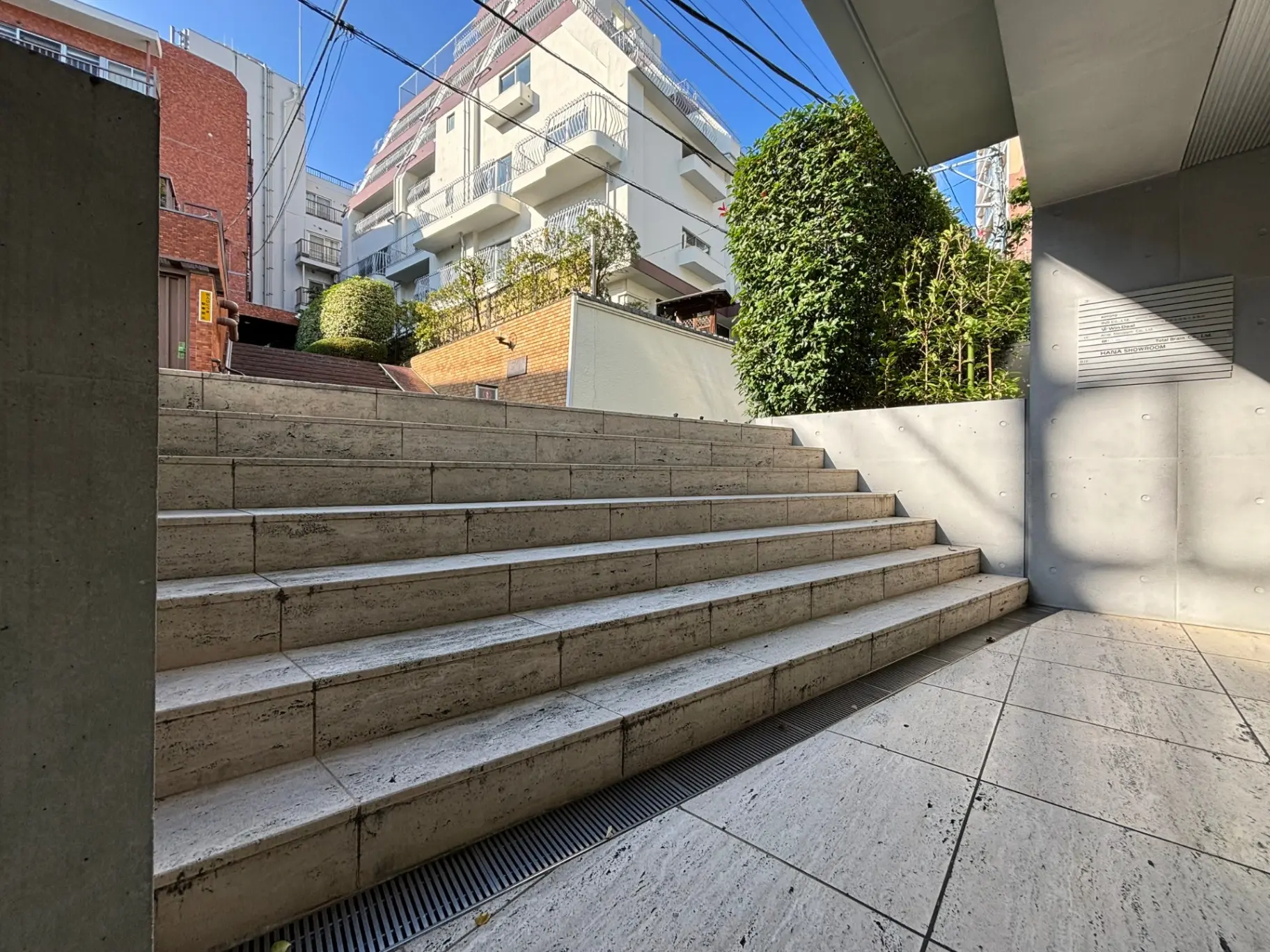 都市のアパートメントに隣接したコンクリートの階段と緑豊かな植栽、日差しが差し込む都会のオープンスペース