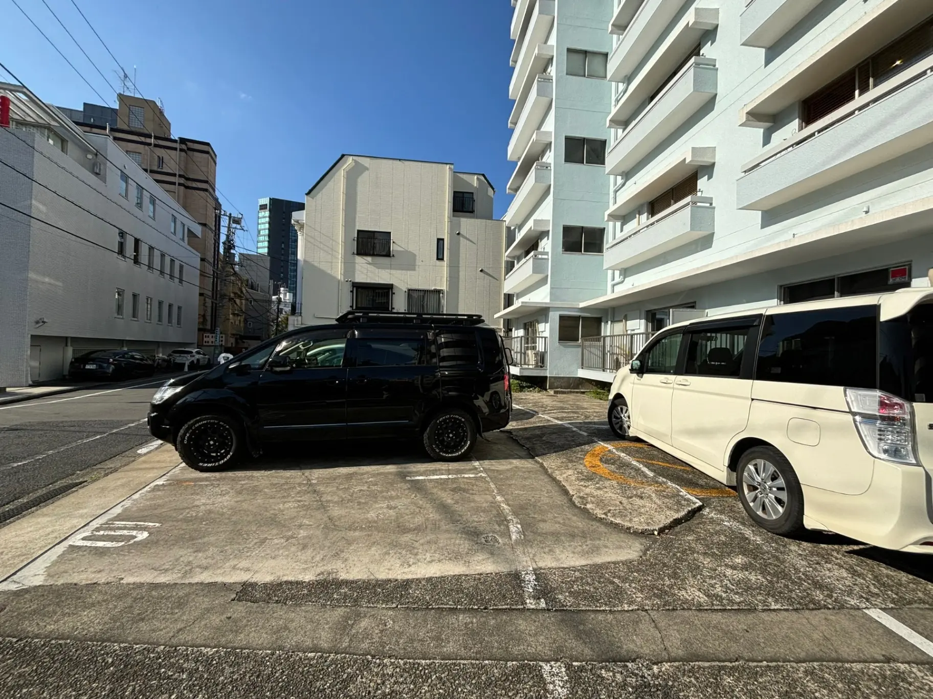 日本の都市部にある駐車場、隣接するアパートの建物と晴れた青空
