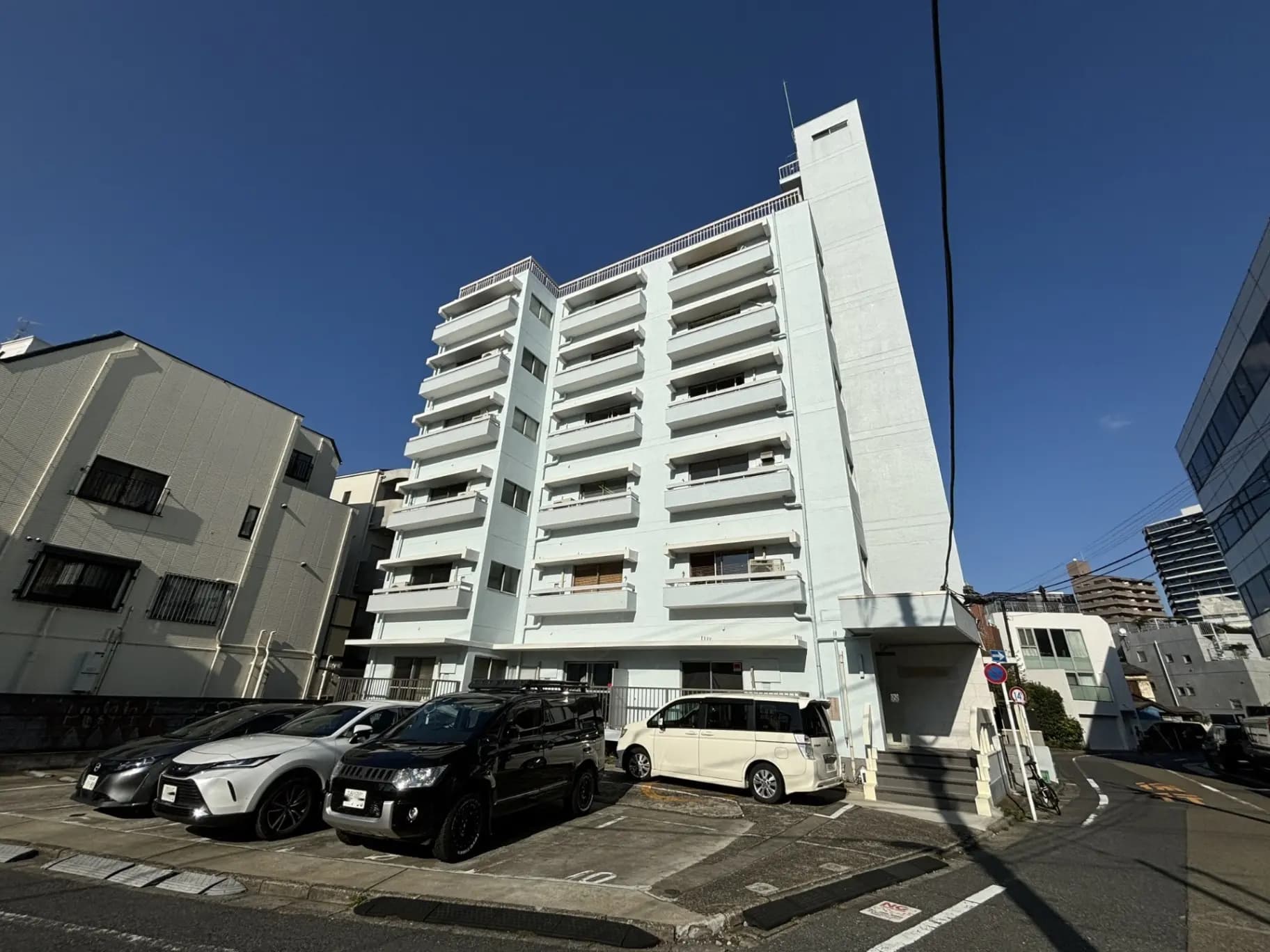 現代的なマンションの外観、晴れた日に撮影された駐車場付きの白い建物