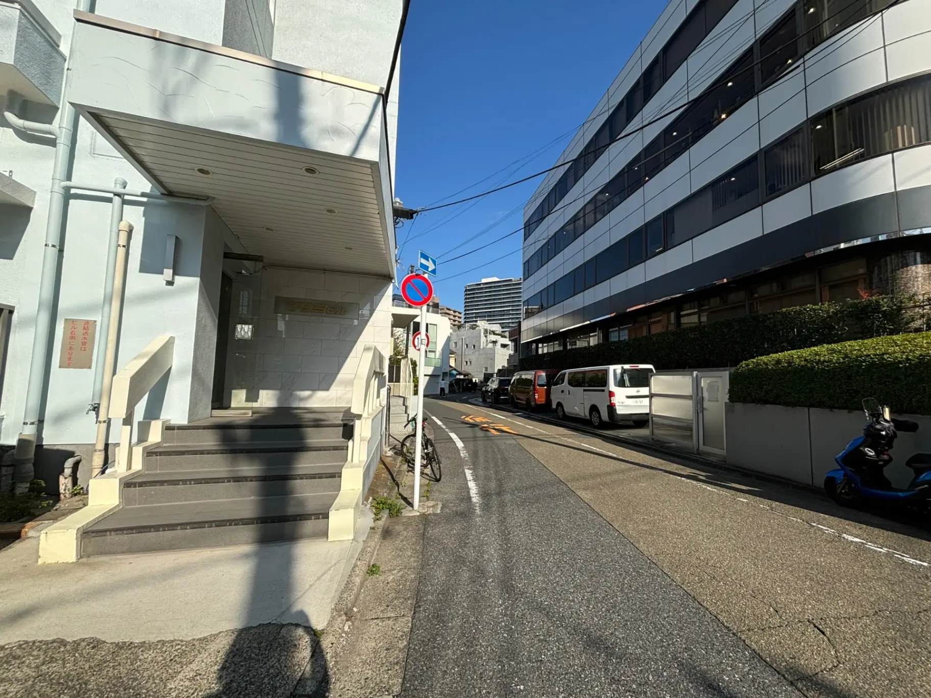 晴れた日の都市風景、建物入口と通行禁止標識が見える狭い通り