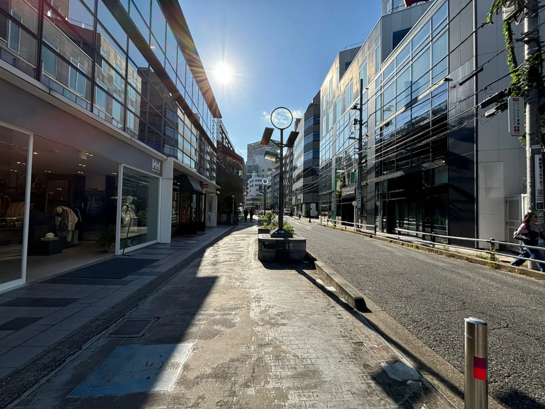 明るい日差しの中、モダンな建物が立ち並ぶ都市の歩道、ショッピングエリアの風景