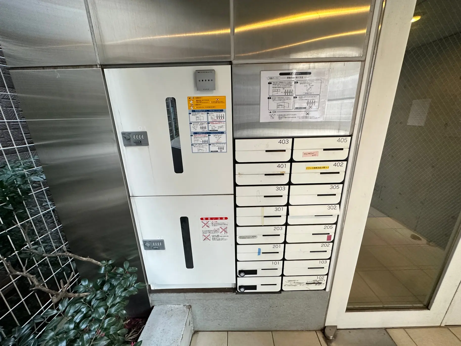 マンションのエントランスに設置された郵便受け、各部屋番号が記載されたボックスと宅配ボックス