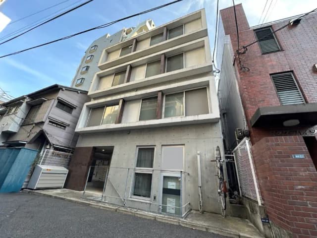 日本の都市部にあるコンクリート造りのマンションとレンガ造りの建物、自転車が置かれた路地