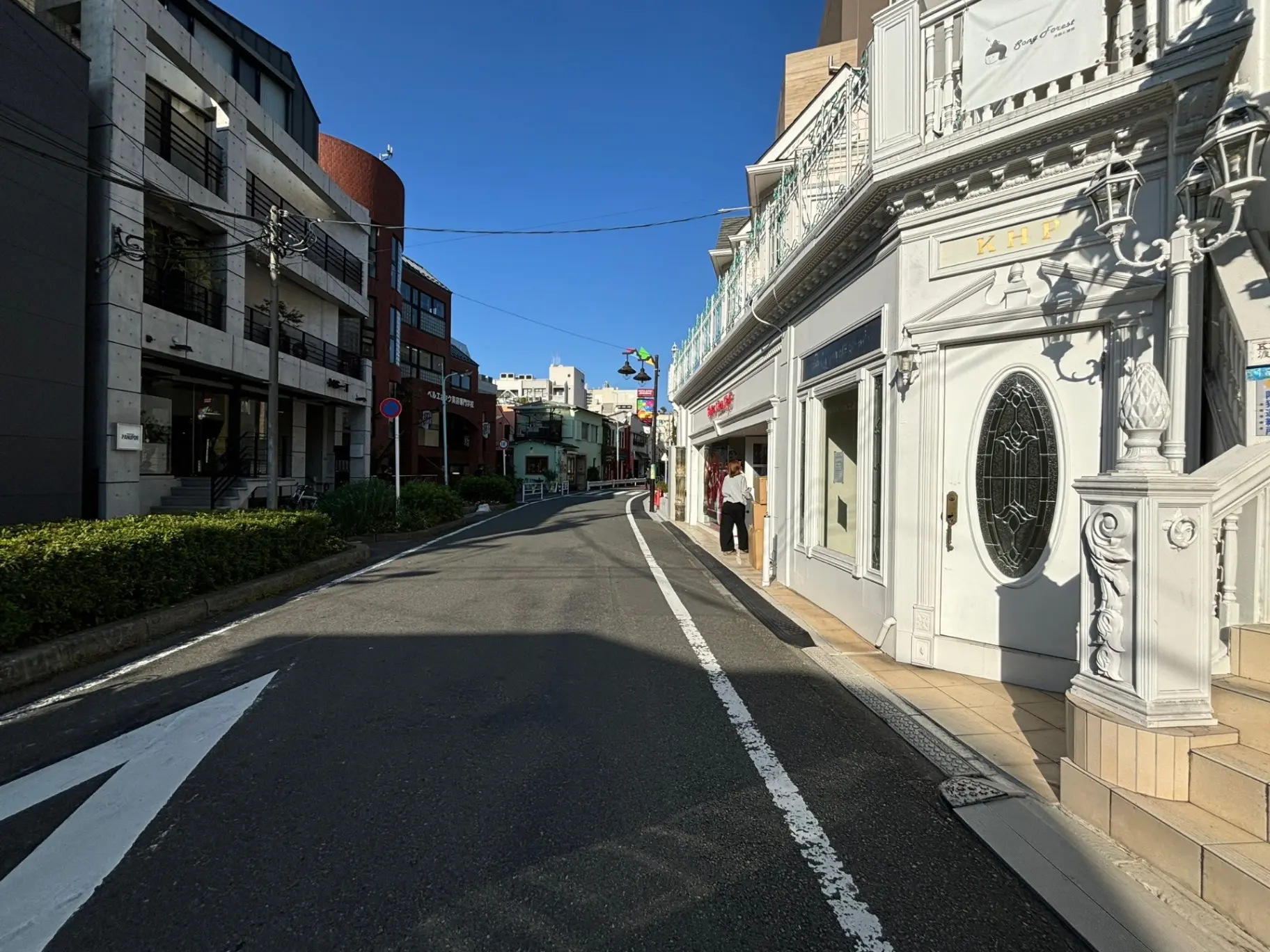 晴れた日の都市の通り、様々な建築スタイルの建物、歩行者と青空