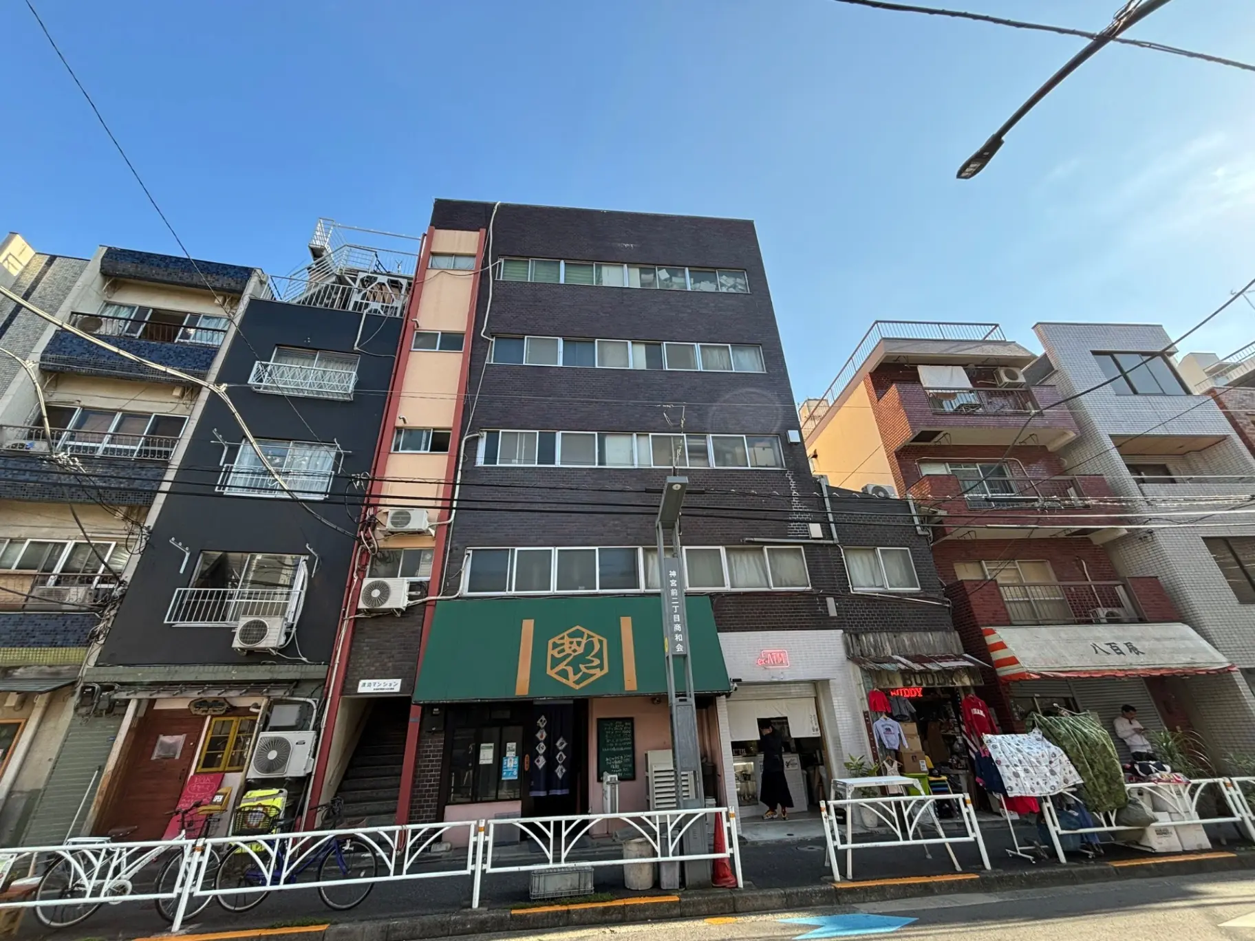 日本の都市部に位置する多様なデザインの住居ビルと商店、晴れた日の青空