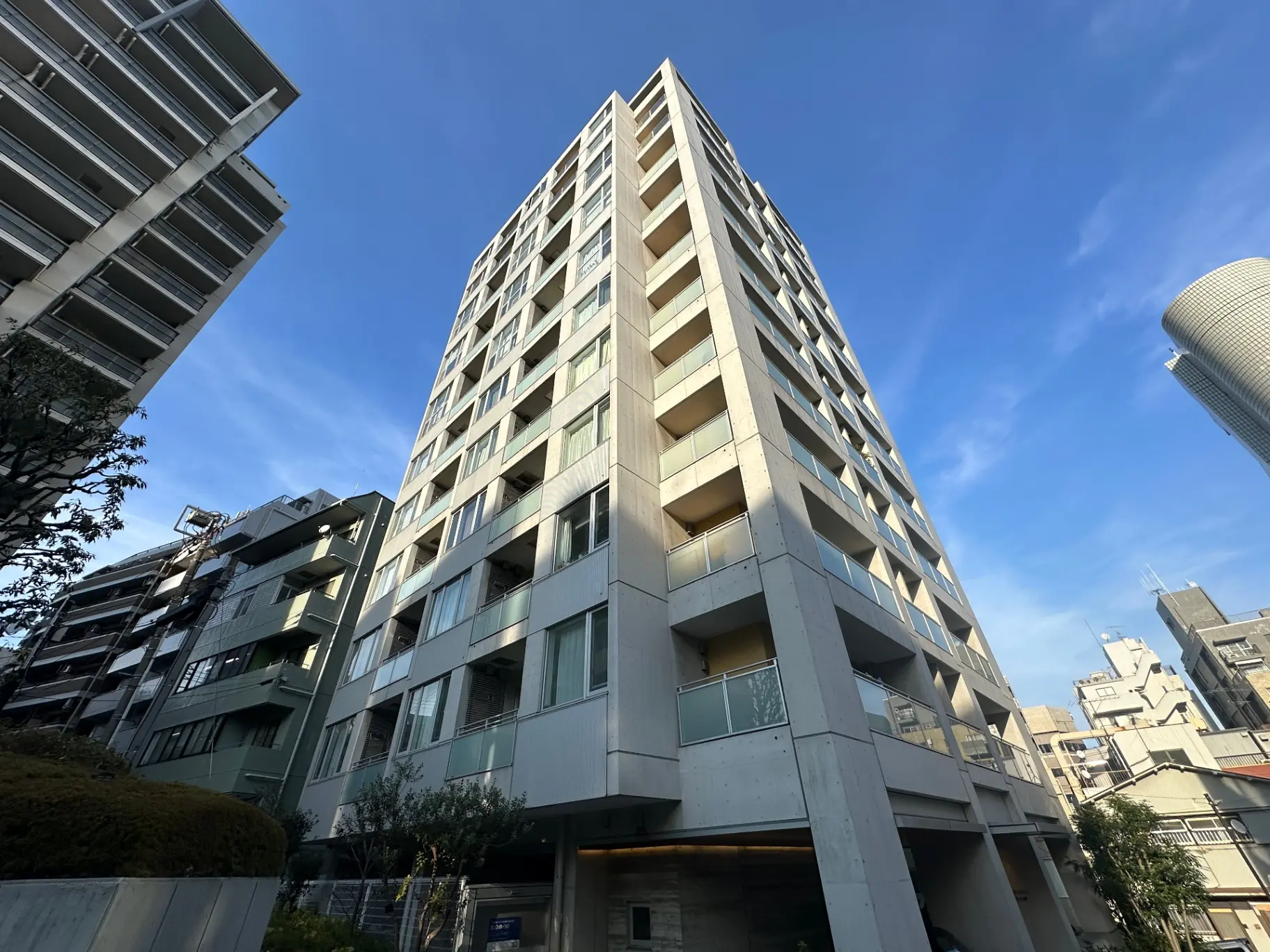 都市の景観に溶け込む近代的なマンションビル、青空と高層建築が見える外観