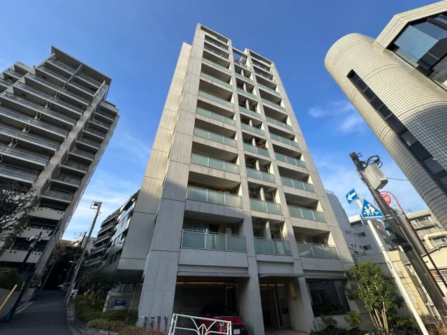 都市風景のマンション外観、現代的なデザインの建物、碧い空と緑の木、交通標識と街灯のある道路