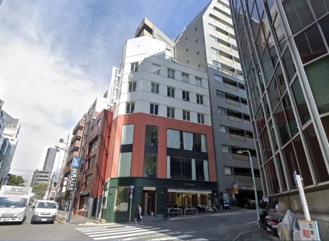 都市の交差点に面した現代的なビルと店舗、青空のもとでの明るいストリートビュー
