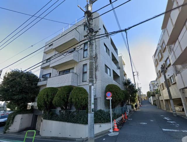 日本の住宅街にある現代的なアパートビル、電柱と配線、晴れた日の青空