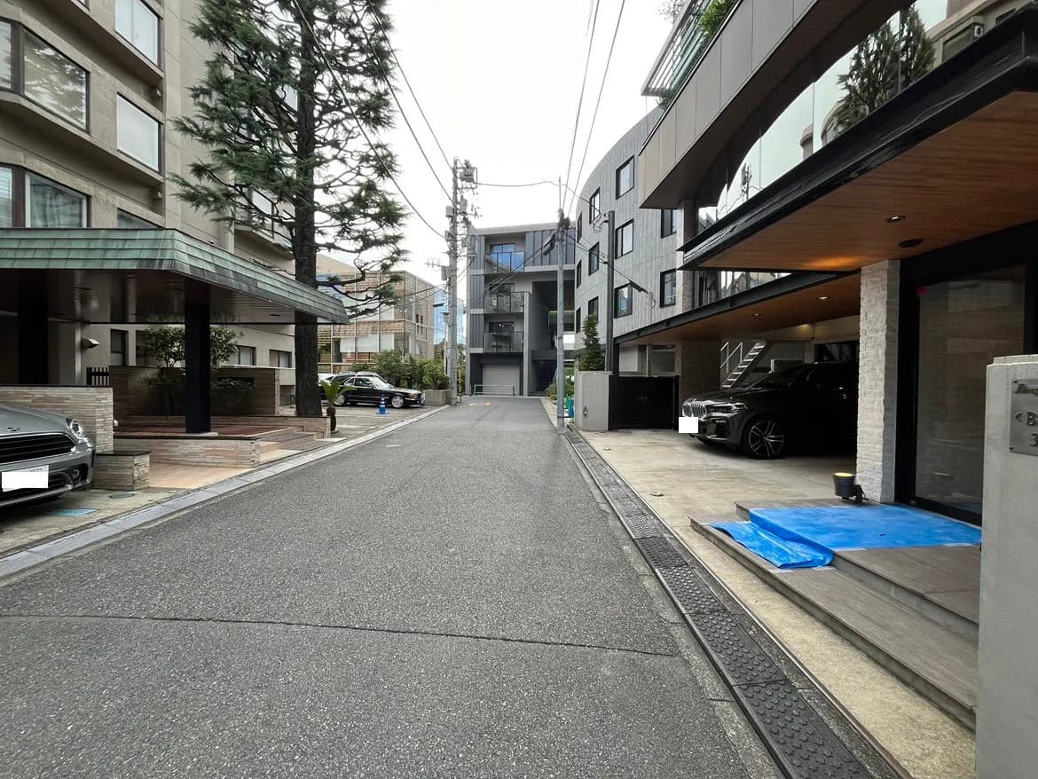 - 都市部の住宅街、モダンな建物とカーポート、静かな通りに立つ高木のある風景