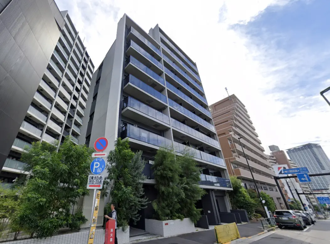 - モダンな外観の集合住宅、広々としたバルコニーを持つ5階建ての建物と周辺の街並みが広がる風景