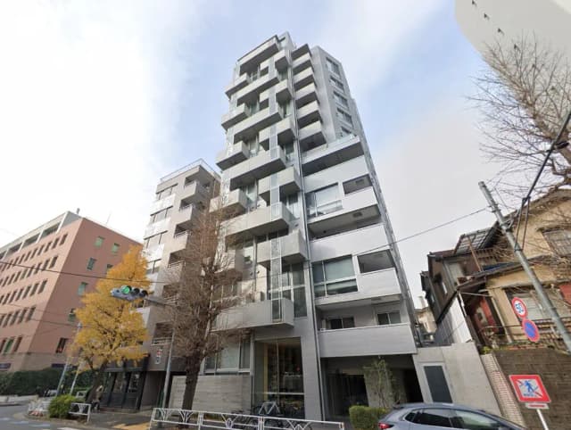 - 現代的なデザインのマンションの外観、青空を背景に高層階のバルコニーとガラス窓が特徴的な建物