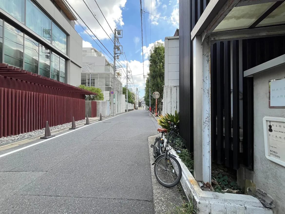- 静かな街並みに停まる自転車と近代的な建物、青空と白い雲が広がる風景の写真