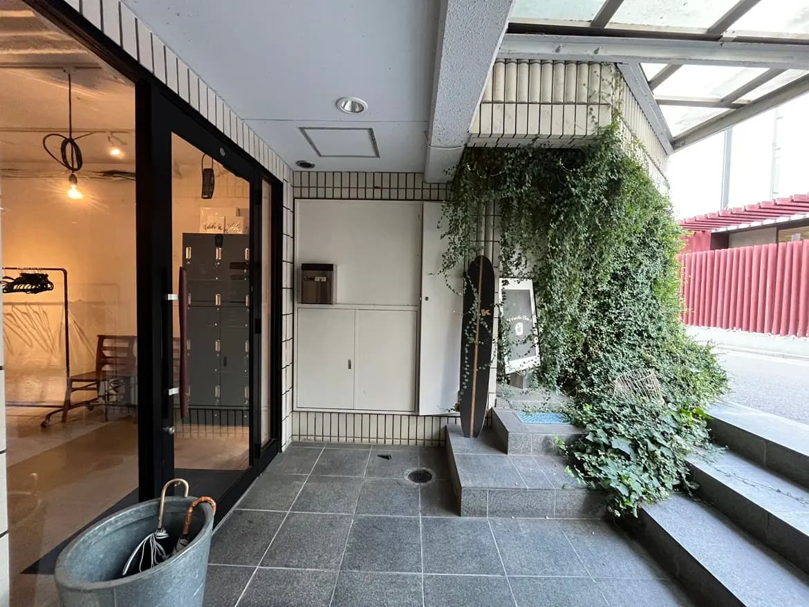 - 現代的なエントランス、黒いガラスドア、植栽に囲まれた入口、灰色のタイルとシンプルなデザインのインテリア