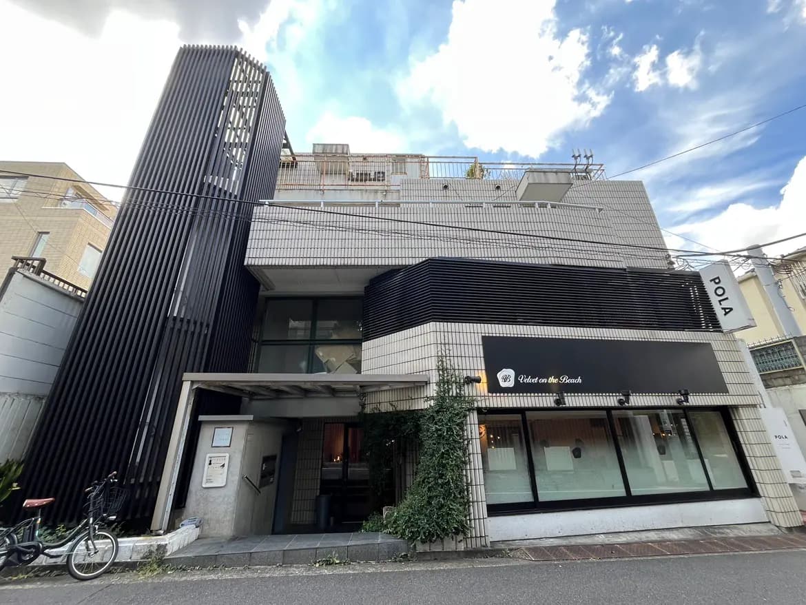 - モダンな外観の建物、黒い縦格子のデザインと白いタイル張り、店舗の看板と自転車が並ぶ街並み