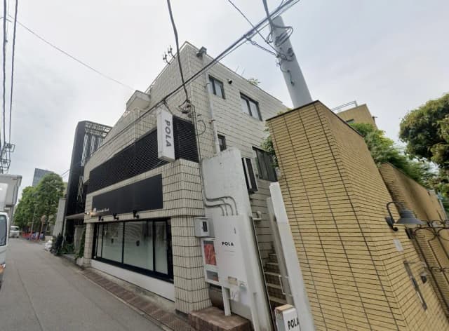 都市の角にある現代的なビルと店舗の外観、歩道と街路灯が見える風景