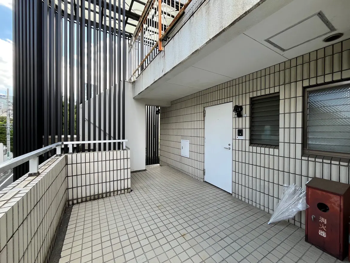 - モダンなデザインのベランダ、白い壁とタイル舗装、階段と窓があるシンプルなエントランススペース