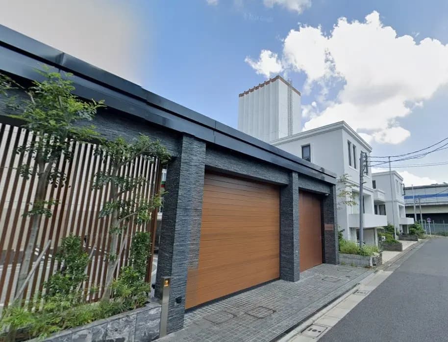モダンで洗練された外観の住宅、木製ガレージドア、隣接する垣根と植物装飾