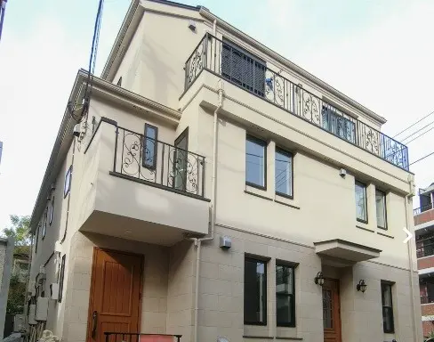 エレガントなデザインの都市型一戸建て住宅、ベージュの壁とおしゃれなバルコニーの鉄製フェンス