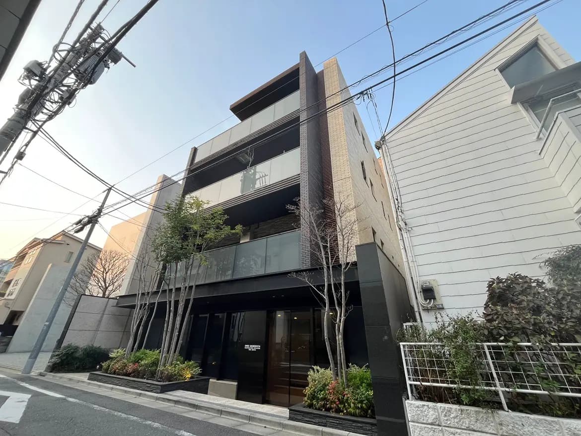 現代的な外観のビル、植栽された街路樹、明るい街中のオフィースまたはアパートメントビル