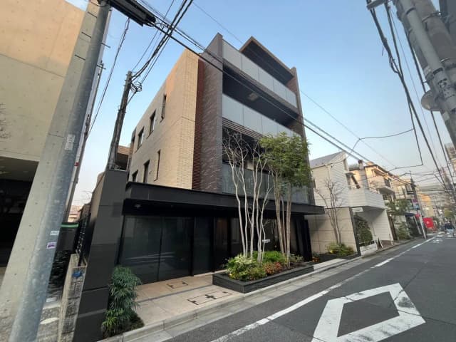 モダンで洗練された外観の都市型ビル、通りに面して建つ、小規模な樹木と植栽がある