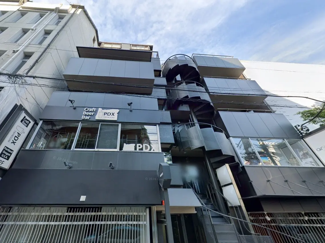 現代的な外観のビルディング、螺旋階段とクラフトビールバーのサインが特徴的な都市のストリートビュー