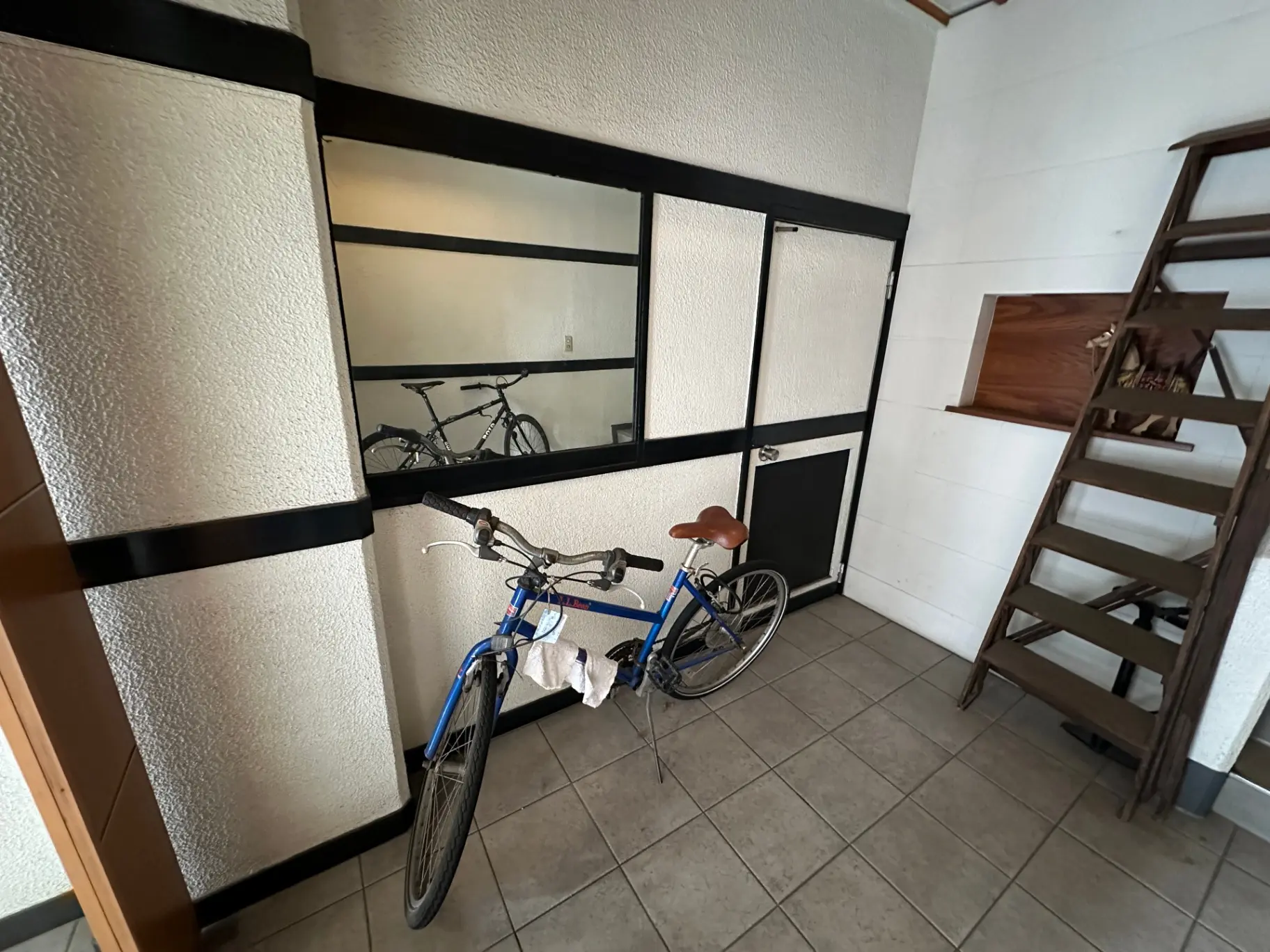 和風の玄関、黒フレームの障子紙の窓、青い自転車と木製の梯子が置かれたインテリア