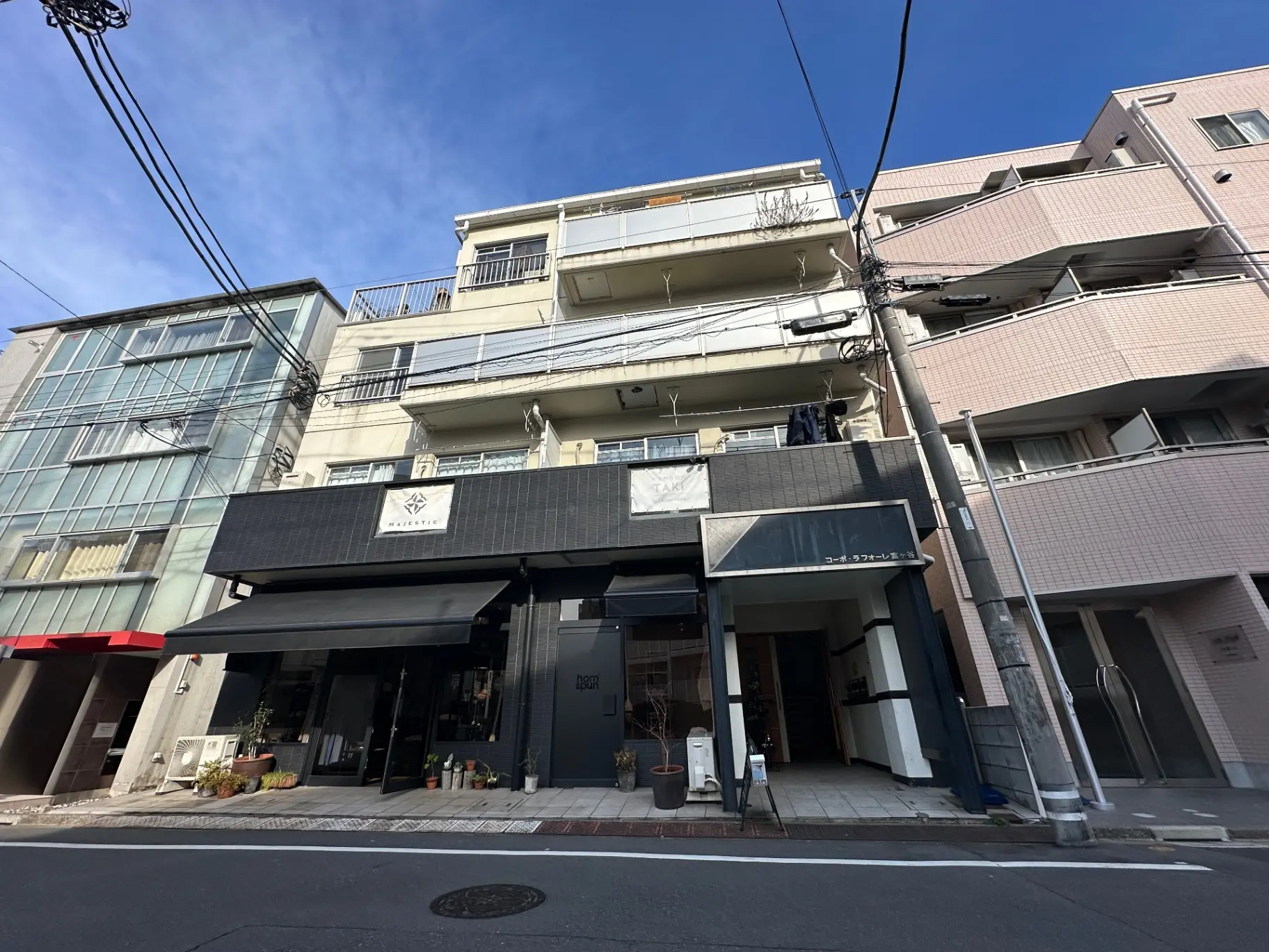 街中の商店街にあるモダンなデザインのビルと店舗、青空が広がる晴れた日の景色