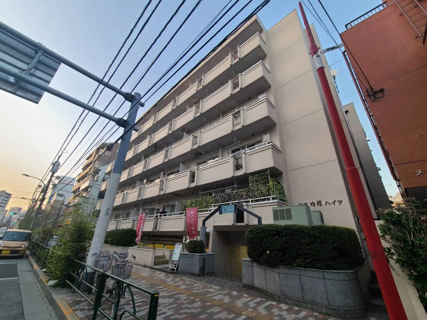 都市型マンションの外観、ベランダに植物、隣接する建物との間の通路