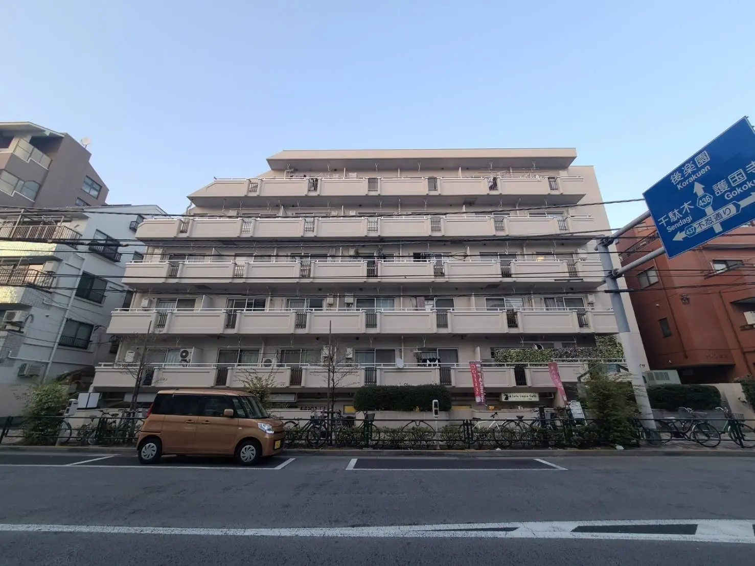 都心に位置するモダンなマンション、バルコニー付きの外観、街路樹と自転車置き場がある景観