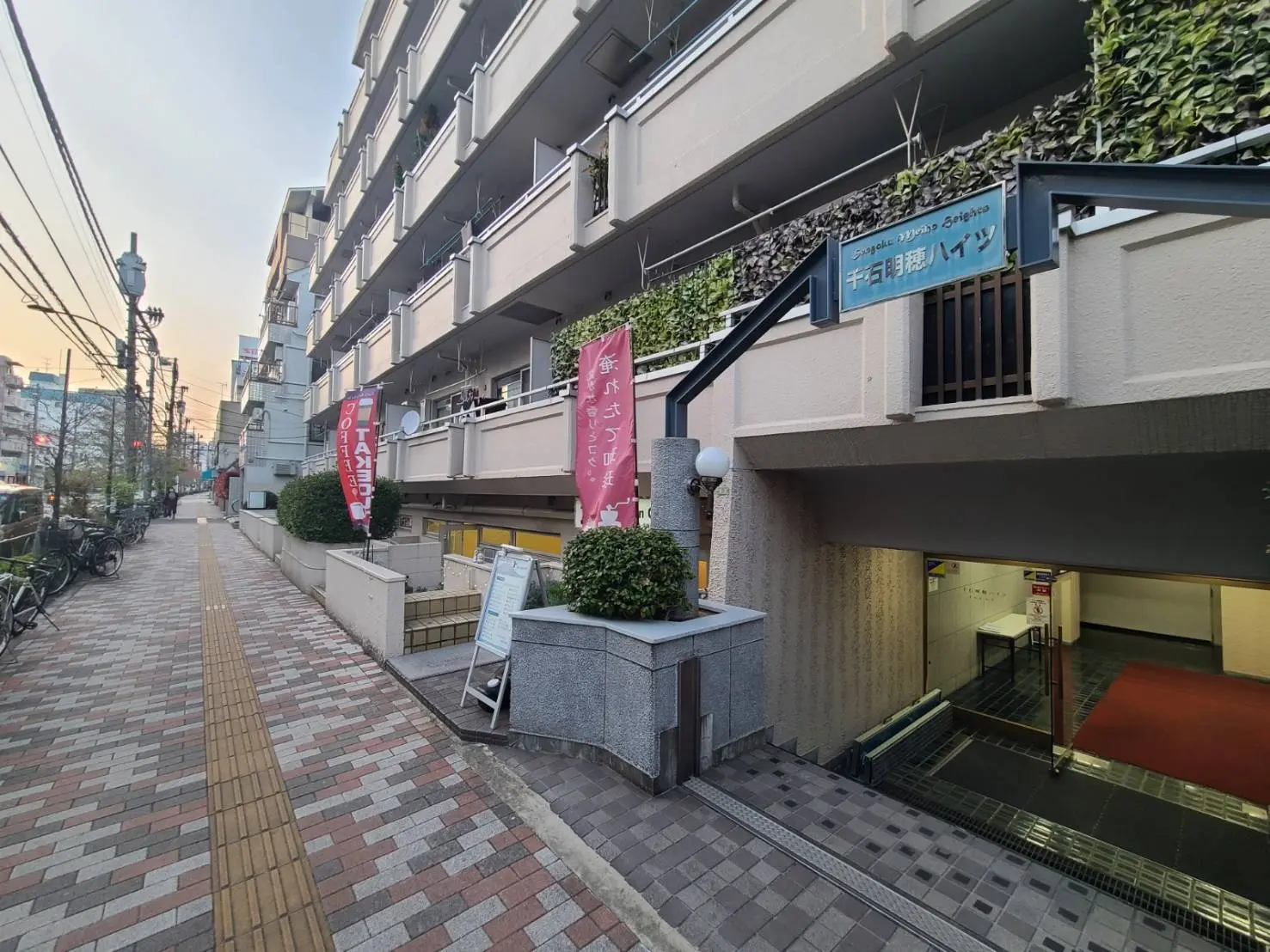 都会のマンションエントランス、駐輪場付き、歩道にタイル張り