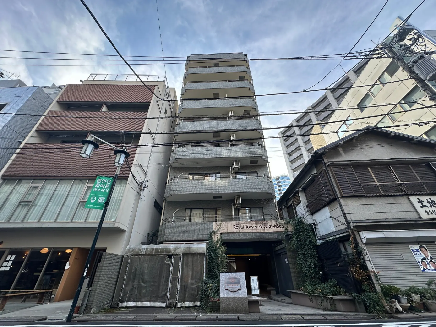 都会的な風景と建物、駐車場入り口、看板、電信柱と配線がある通り