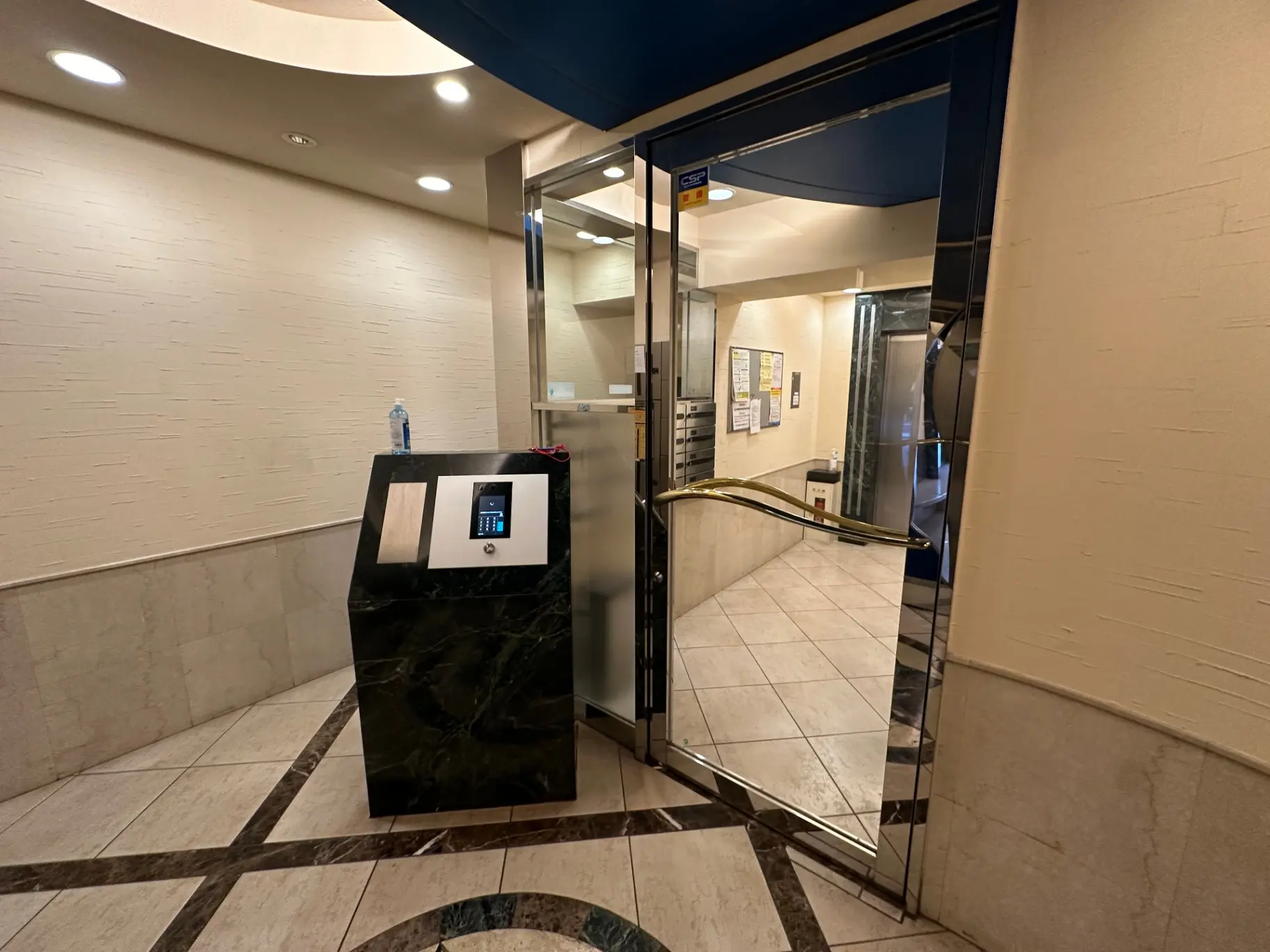 オフィスビルのエントランスホール、自動ドアとエスカレーター、タイル張りの床と壁