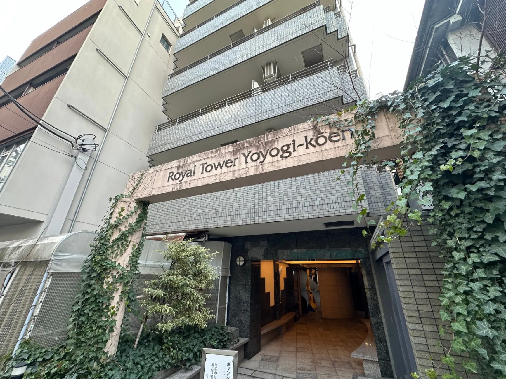ロイヤルタワー代々木公園のエントランス、植物に覆われた高層マンションの外観