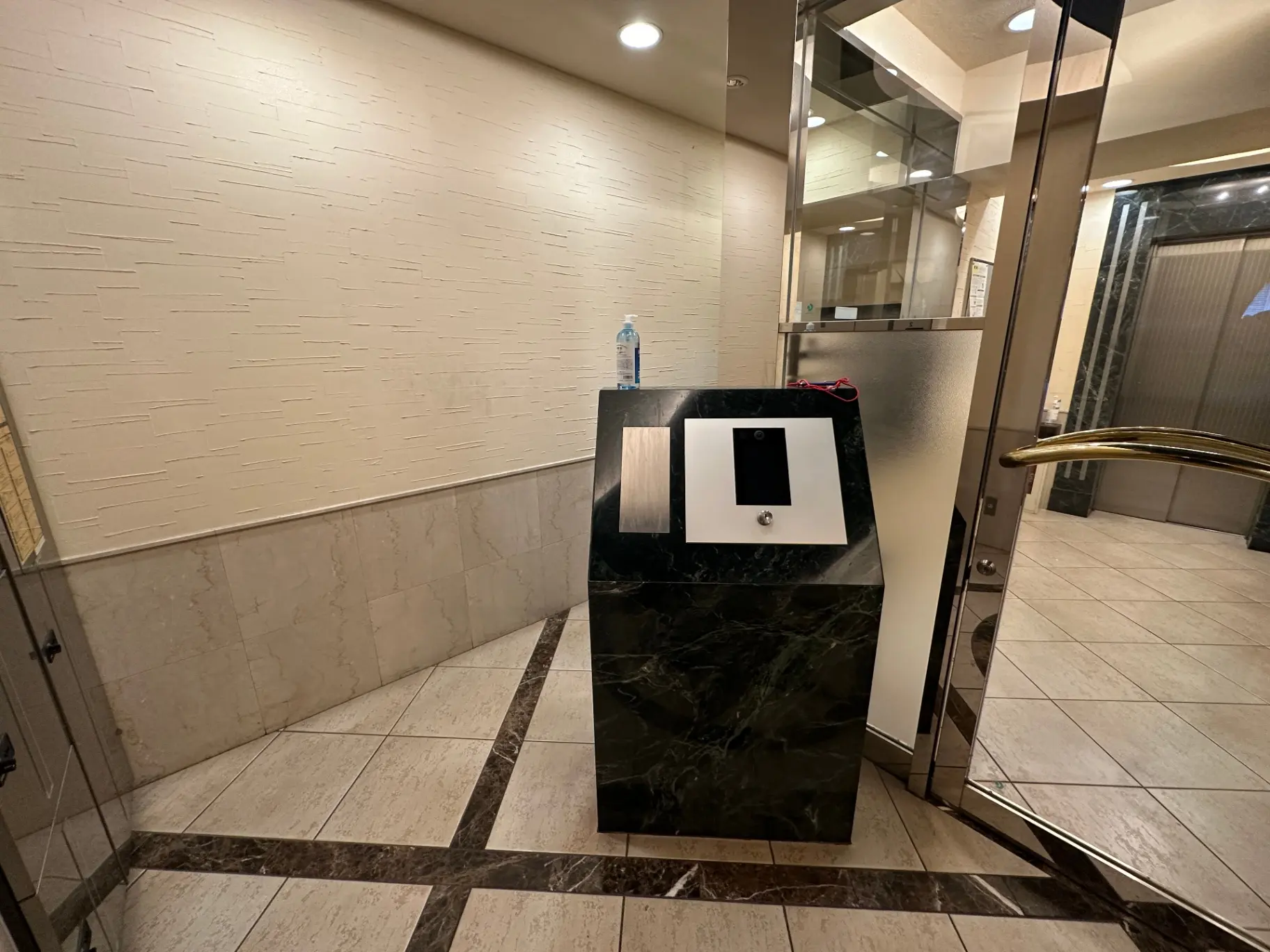 エレガントなデザインのビルエントランス、大理石の床と壁、ステンレス製のエレベータ扉