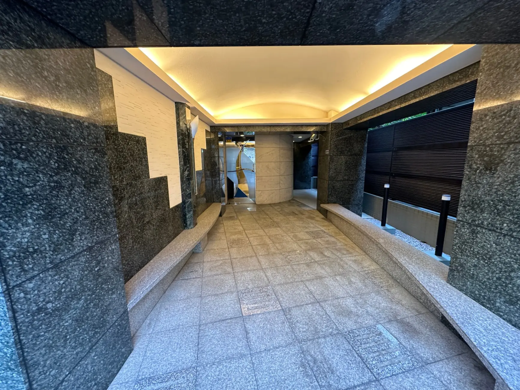 モダンなビルディングのエントランスホール、石材の壁と床、暖色系の照明、快適なアクセスポイント