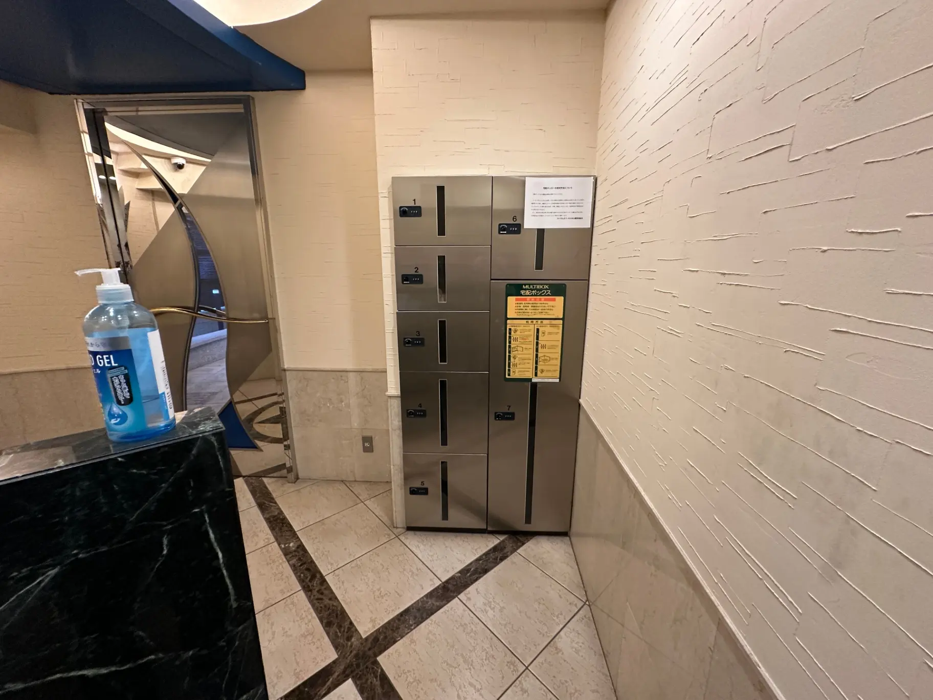 建物内の共用エリアに設置された宅配ボックスと消毒ジェルスタンド