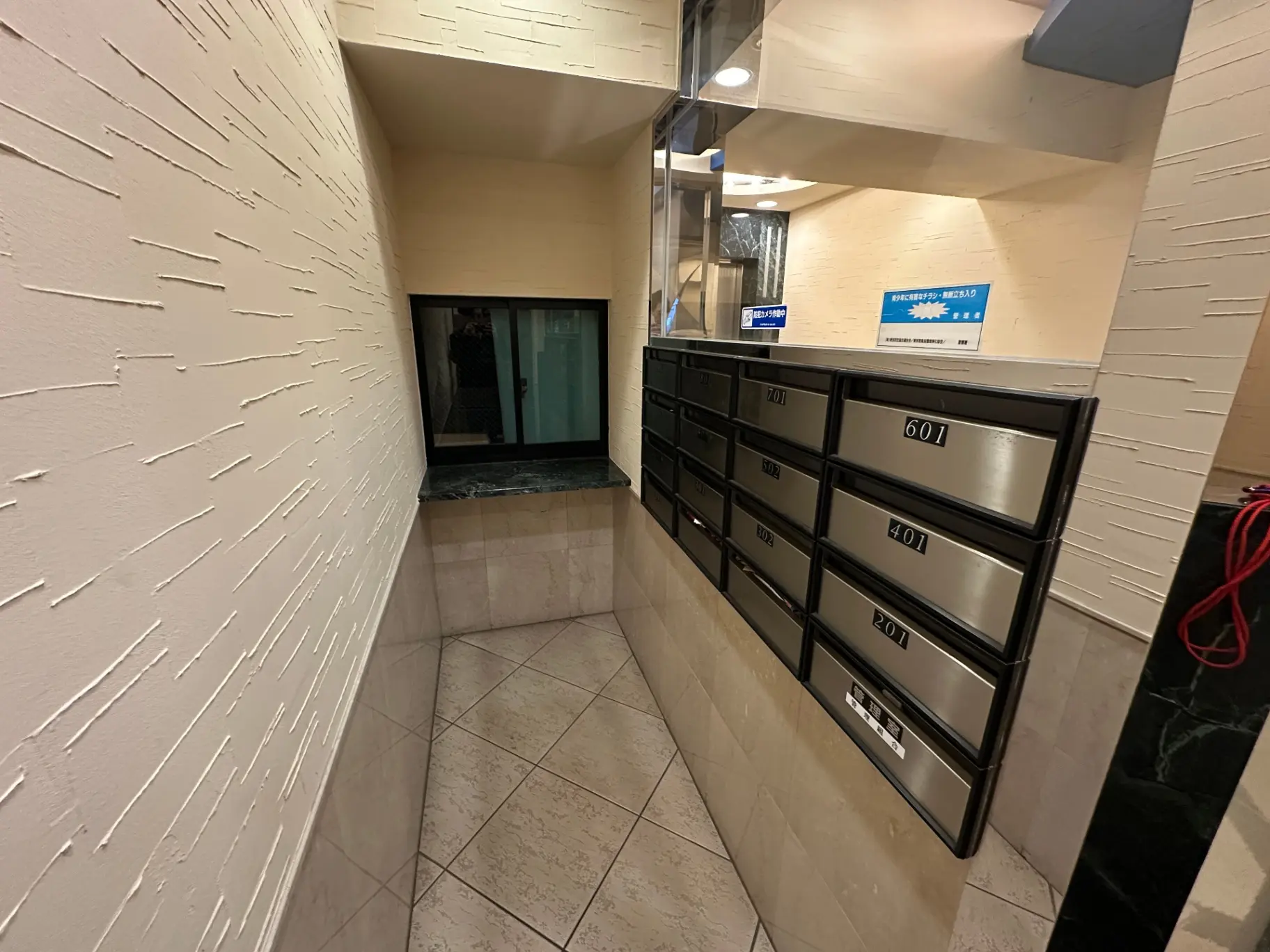アパートメントのエントランスホール、郵便受けとインターホン、清潔感のあるタイル仕上げ