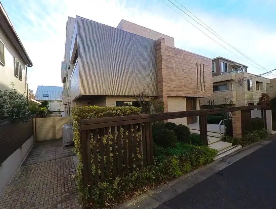 - 現代的な外観の住宅、洗練されたデザインの外壁、緑豊かな庭と駐車スペースのある街路風景