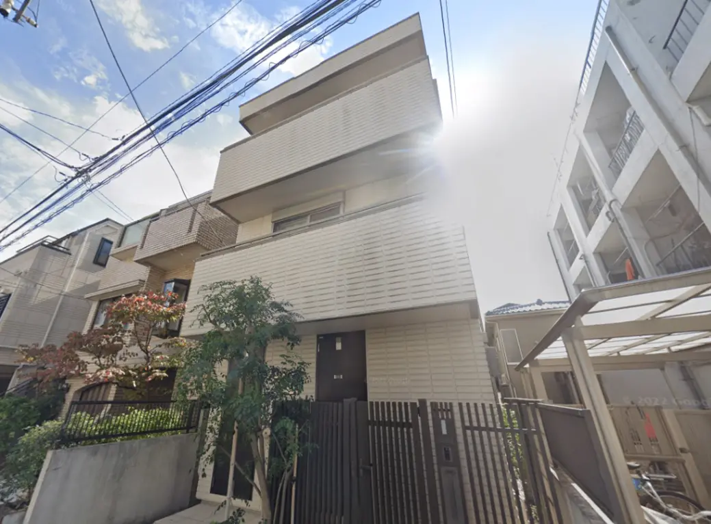 - モダンな外観の住宅、シンプルなデザインのファサードと緑豊かなエントランス、周囲の住宅と調和した落ち着いた雰囲気