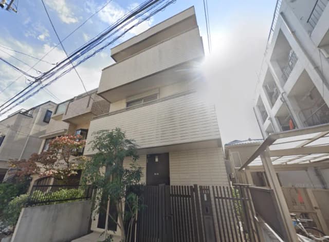 - モダンな外観の住宅、シンプルなデザインのファサードと緑豊かなエントランス、周囲の住宅と調和した落ち着いた雰囲気