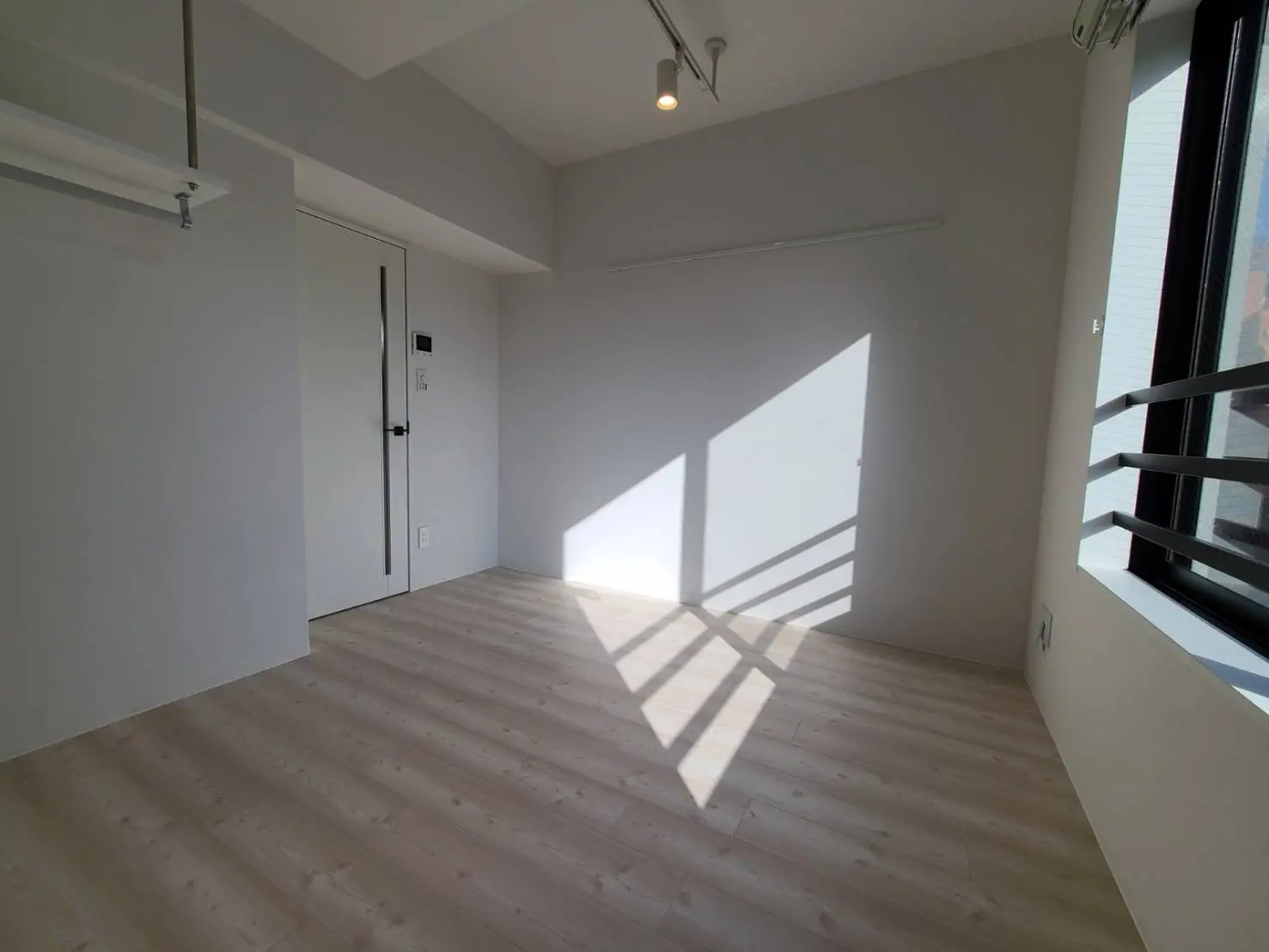 シンプルで明るいモダンな部屋、ナチュラルウッドのフローリングと大きな窓から差し込む光